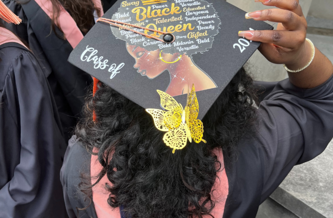 Photo of an MPH student with showing their graduation cap they decorated with motivational quotes