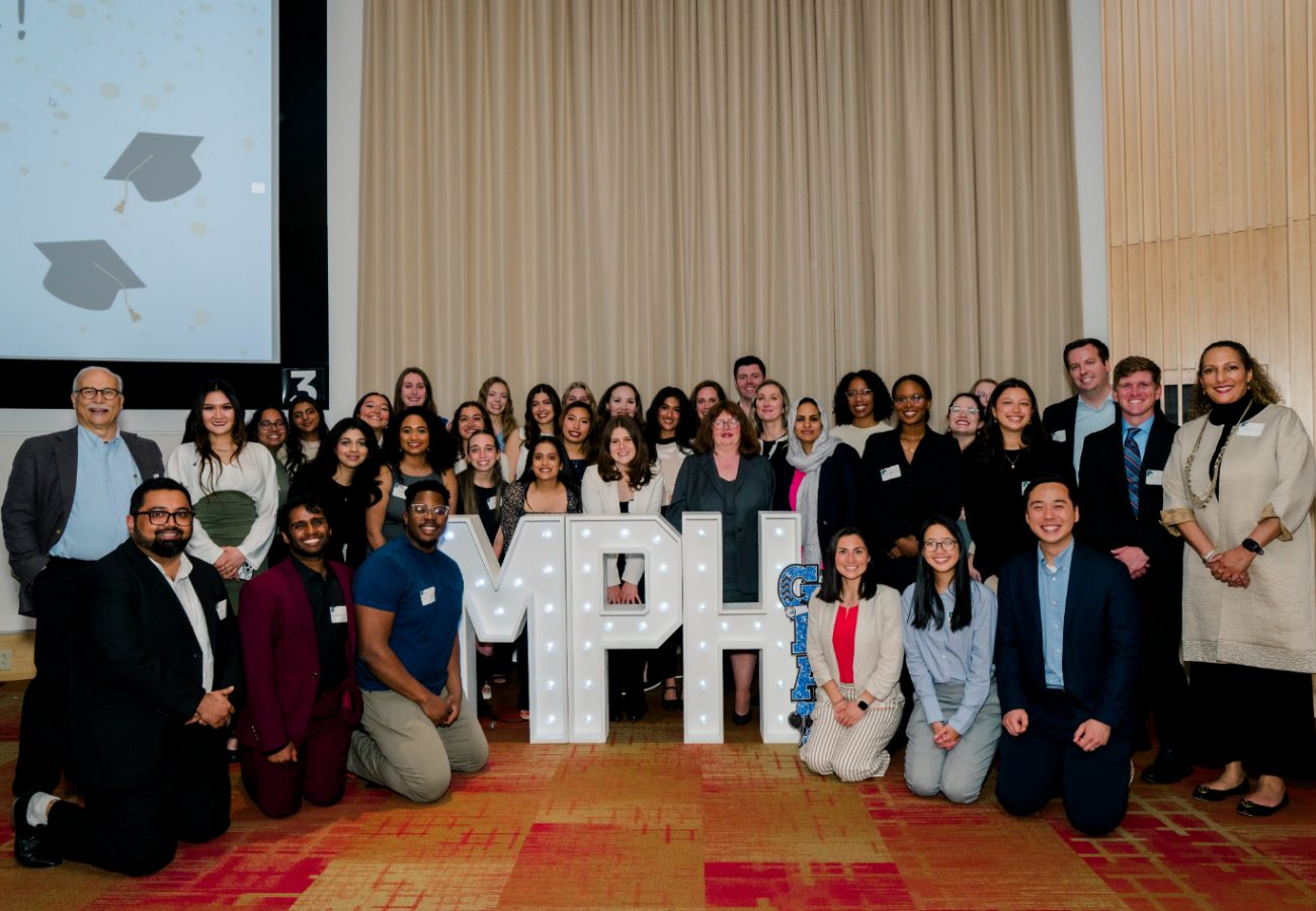 Group of MPH graduates smiling around MPH letter sign smiling