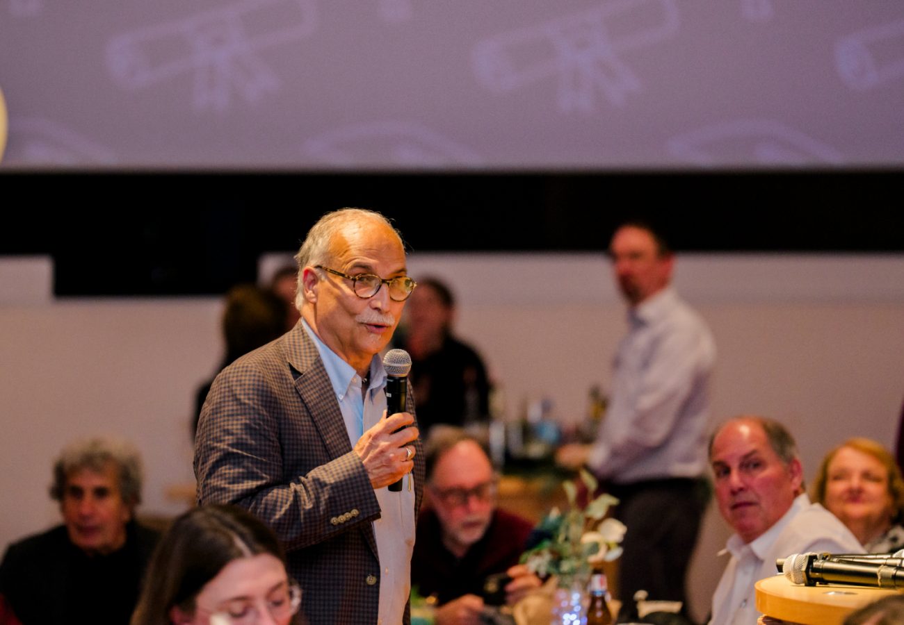 David Gregorio holds mic and speaks to attendees at graduation dinner