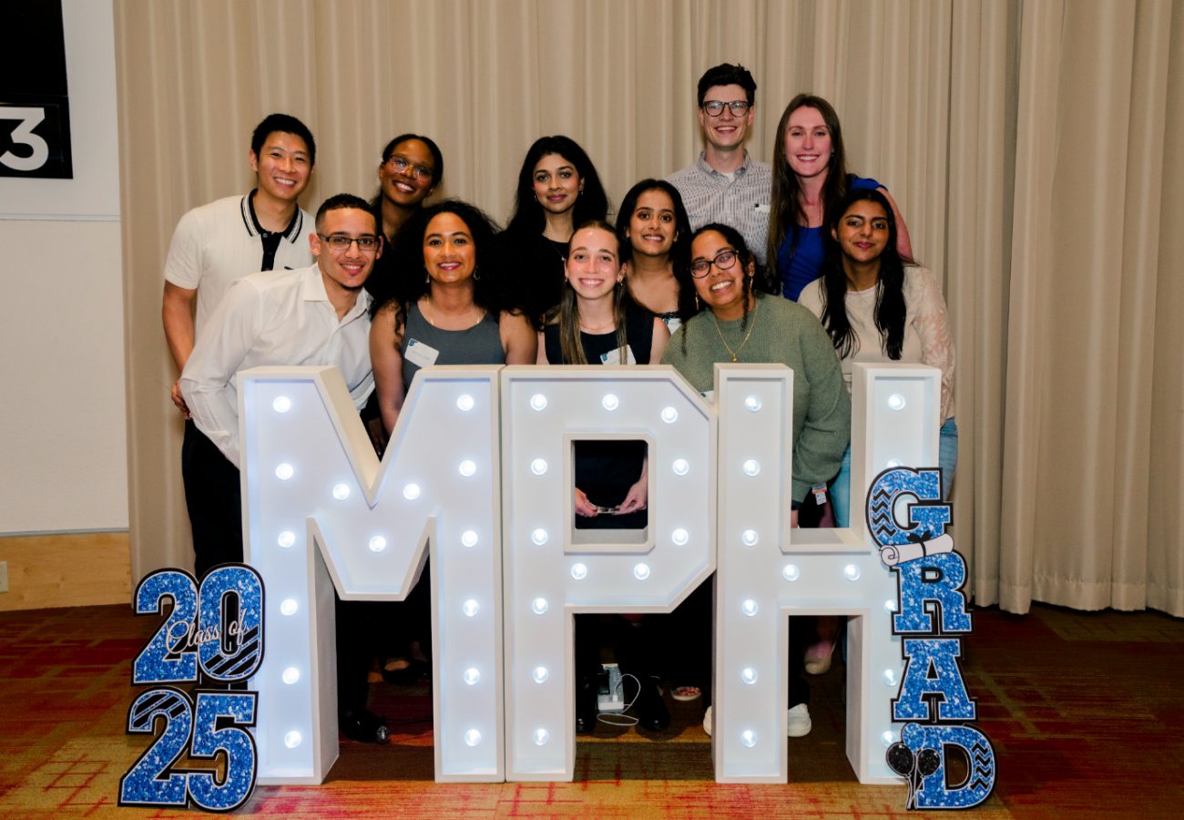a group of students and guests smiling behind MPH letter sign